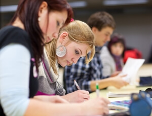 pretty female college student sitting in a classroom full of students during class symbolising higher education in USA