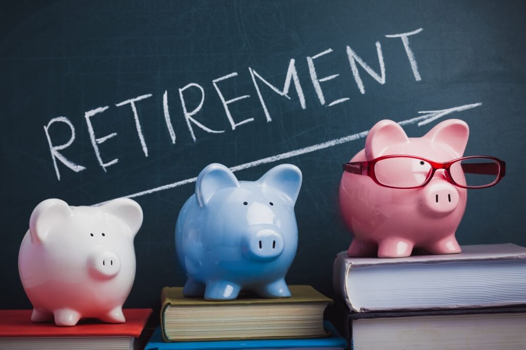 3 piggy banks on top of a book. A blackboard on the background with retirement written in chalk. Retiring abroad concept.