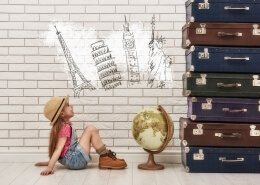 happy child girl against a white brick wall. girl having suitcases and dreaming of traveling. Moving abroad alone concept.