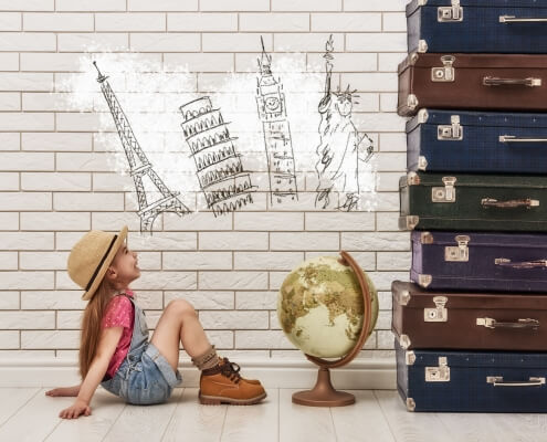 happy child girl against a white brick wall. girl having suitcases and dreaming of traveling. Moving abroad alone concept.