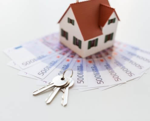 Close up of home model, money and house keys. Real estate investment in 2020 concept