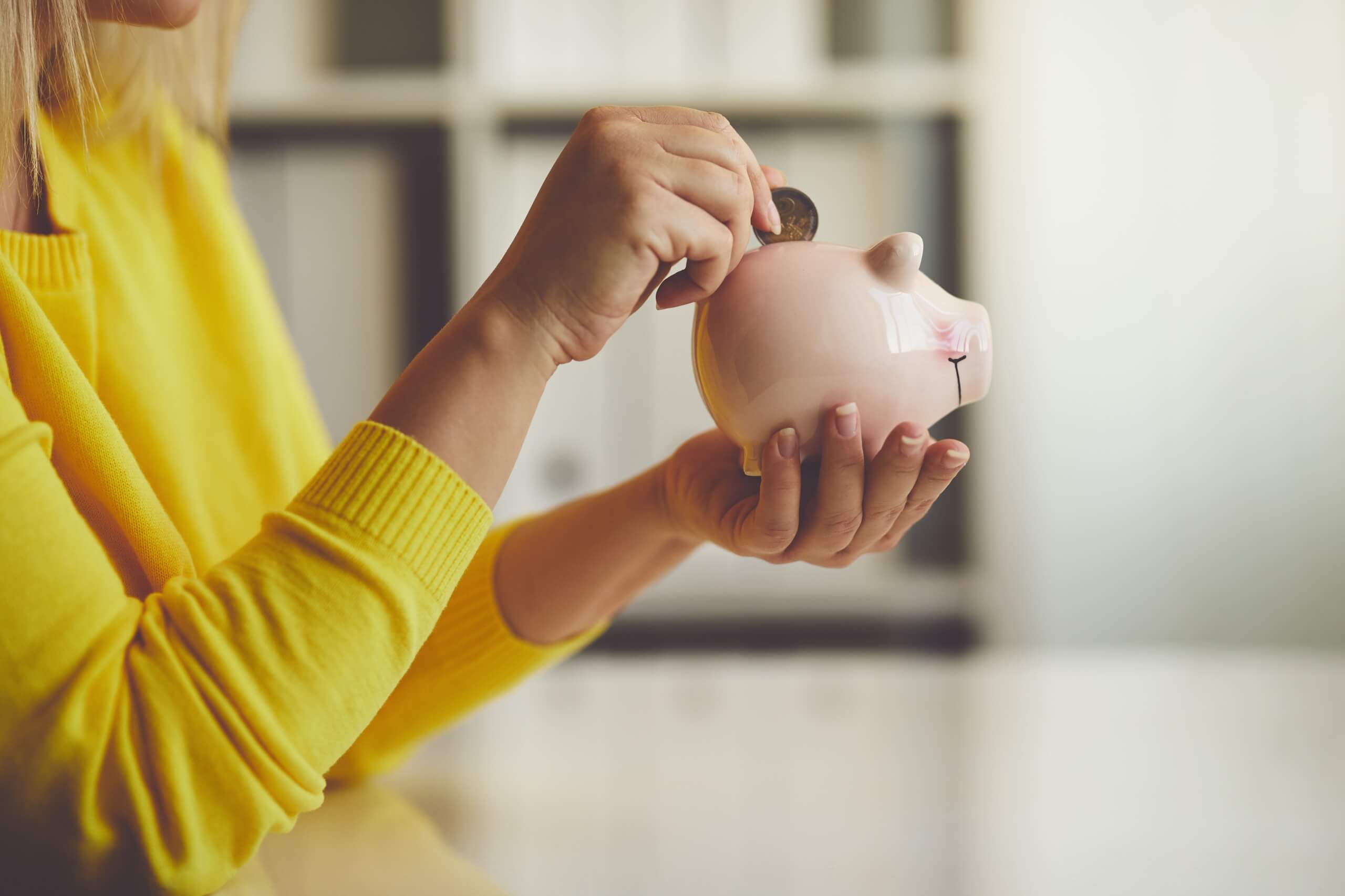 Woman inserts a coin into a piggy bank representation of gender gap