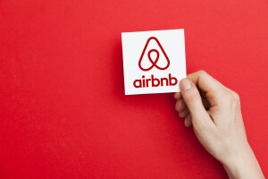 Hand holding Airbnb logo. Airbnb is a popular online home vacation rental company