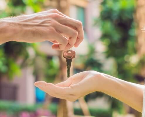 Real estate agent giving keys to apartment owner, buying selling property business. Close up of male hand taking house key from realtor. Mortgage for purchasing flat, getting access to own home after a real estate investment