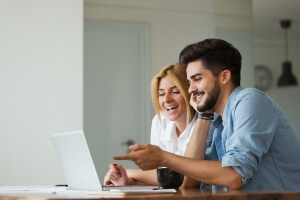Handsome young man and attractive woman working from home together on laptop