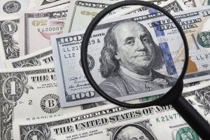 USD dollar and a magnifying galss - US focus on today's data