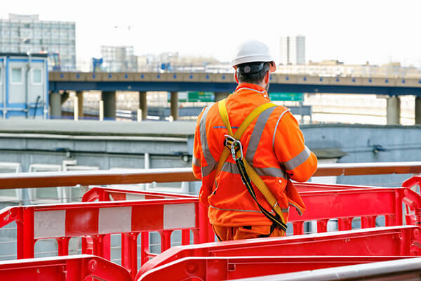 Back view of a construction worker walking into a building site in Canary Wharf - Halo Financial