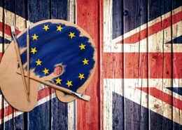 A palette and a brush with the European flag on painting the UK flag on a wall, symbolising the impact of Brexit on UK art.