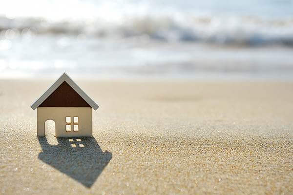 house on the sand beach near sea - Halo Financial