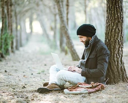 A man with a laptop sitting in the snow. Work from home concept