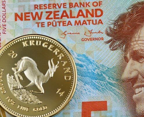 A macro image of a five New Zealand Dollar bill signed by the Reserve Bank of New Zealand with a golden Krugerrand one ounce coin