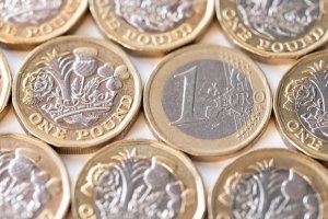 Stack of Euro coins and new pound coins isolated on white background