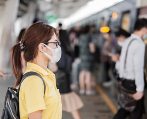 young Asian woman wearing protection mask against Coronavirus in Wuhan at public train station.