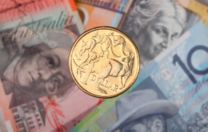 Australian dollar coin and bank notes Symbolising GBP-AUD after RBA cut base rate