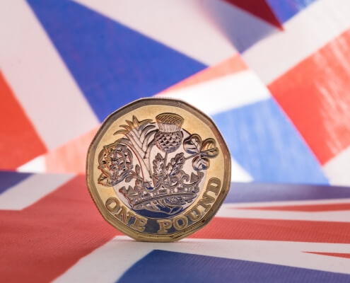New pound coin on union jack flag symbolising Sterling weakness on unemployment data
