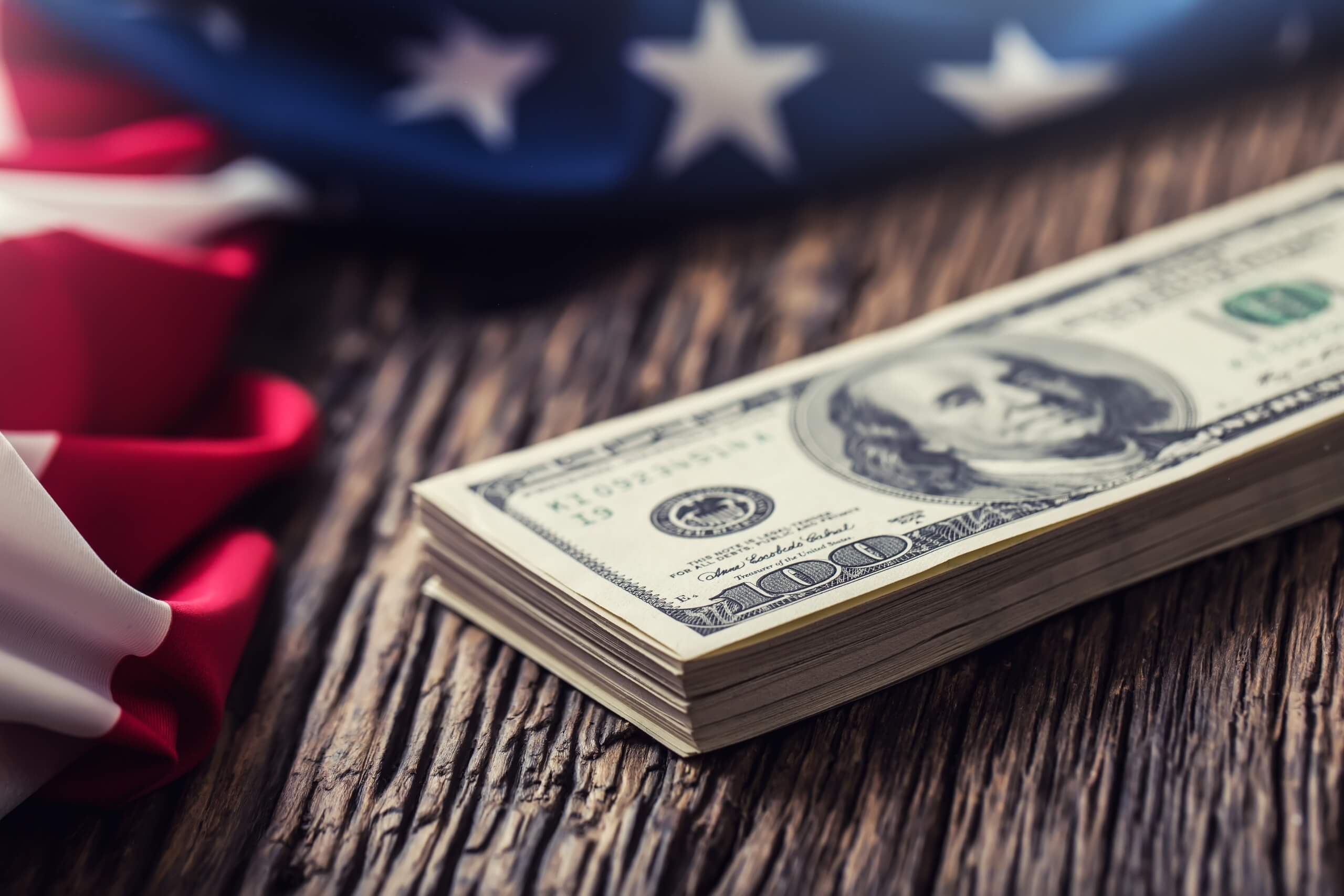  Dólares americanos una bandera de Estados Unidos.Primer plano de la bandera estadounidense y dinero en efectivo en dólares en madera de roble viejo.