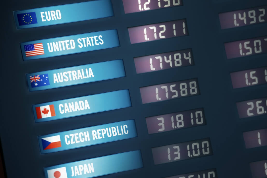Illuminated currency exchange board showing exchange rates for various countries and currencies.