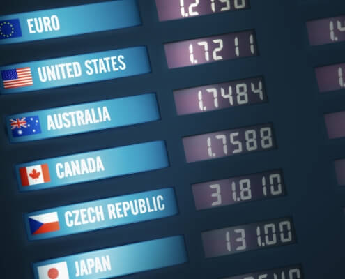 Illuminated currency exchange board showing exchange rates for various countries and currencies.