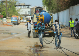 workers sprinkling sanitizer on street