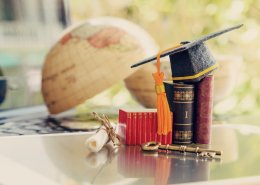 Graduate study abroad program for opening or expand world view concept : Graduation cap or hat, a key, world globe map, foreign text book on laptop, depicts achievement or success in online education