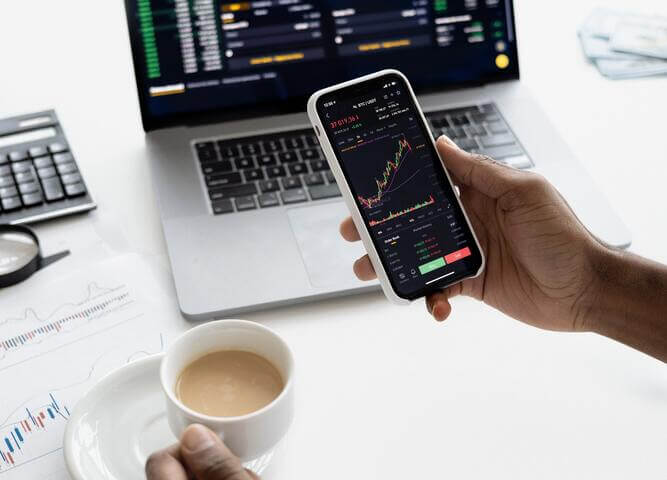 man holding tea cup and looking at stock price