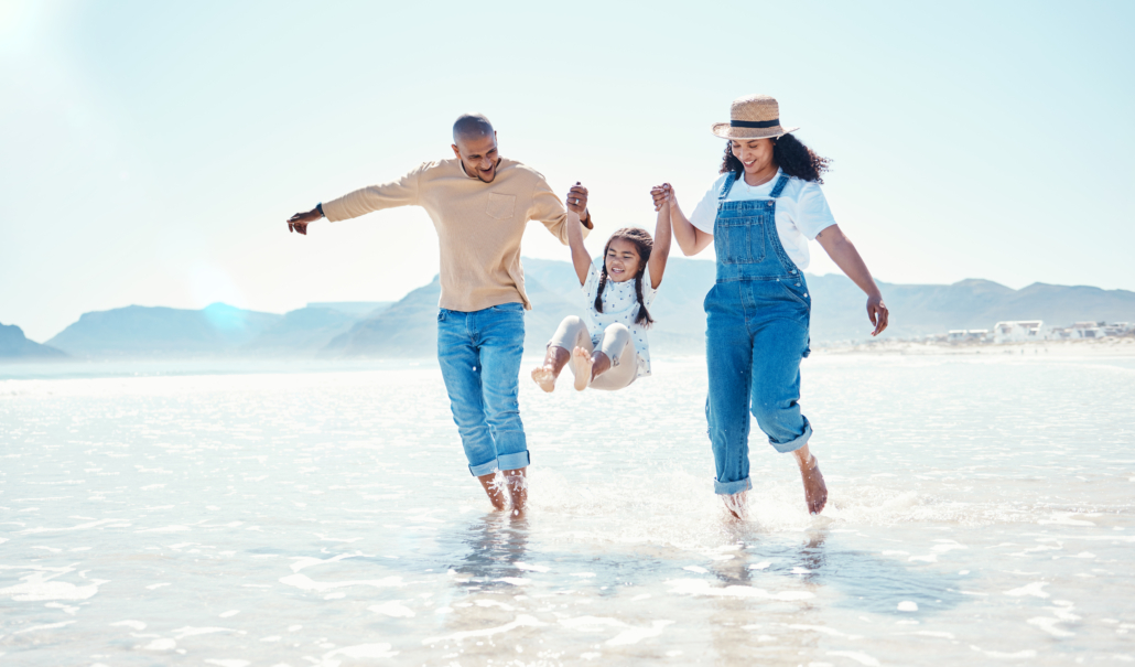 Playing, parents and girl in water at beach